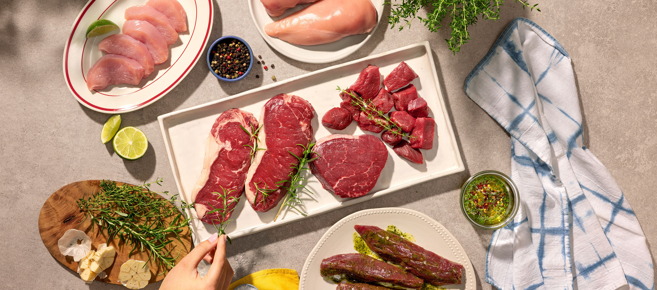 Various cuts of raw meat, including chicken and beef, with herbs and spices.
