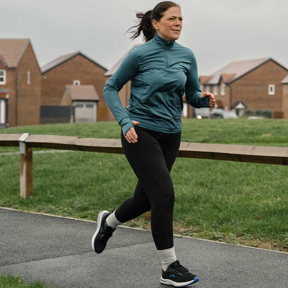 Woman in activewear running on an outdoor path.
