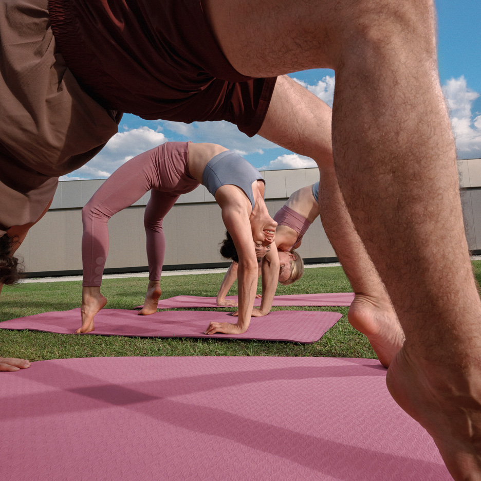 People doing yoga outdoors on yoga mats, wearing activewear.