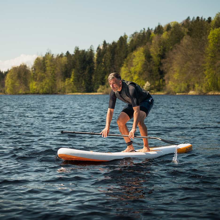 Man paddlar SUP på en sjö.