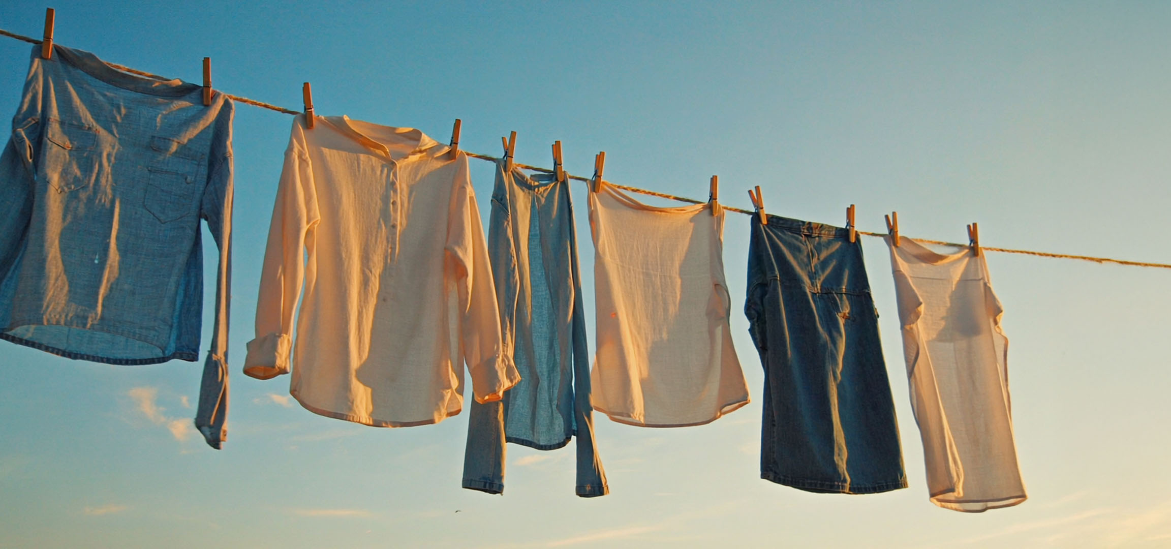 Roupas secando em um varal: camisas e calças jeans.