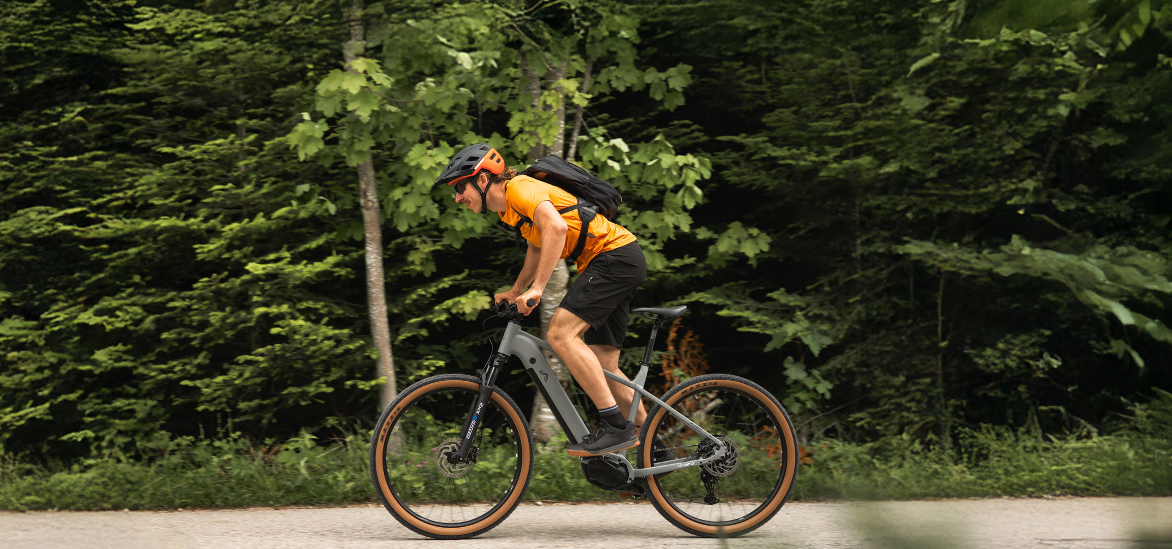Um homem anda de bicicleta elétrica Cube em uma trilha na floresta.