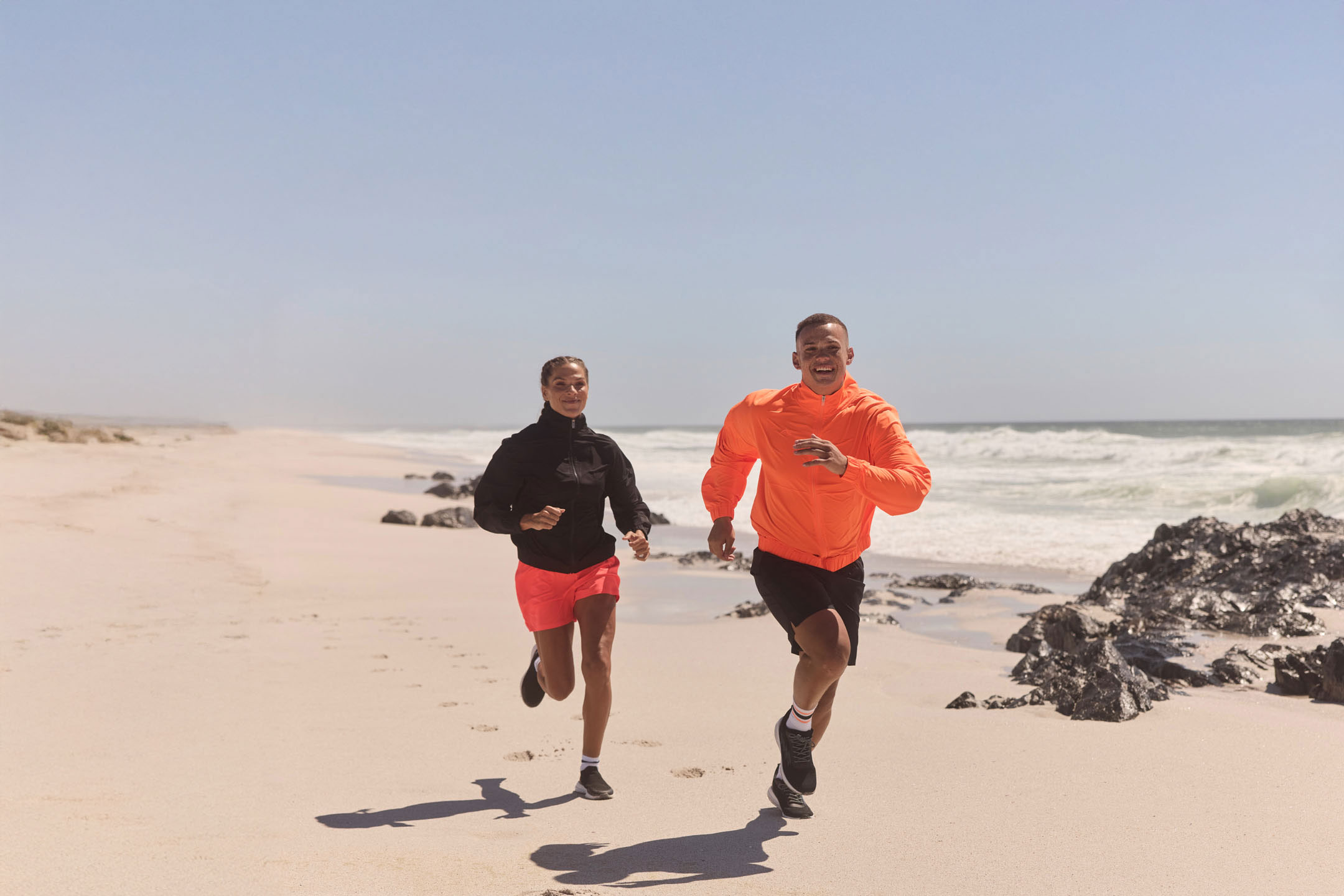 Duas pessoas correndo na praia.