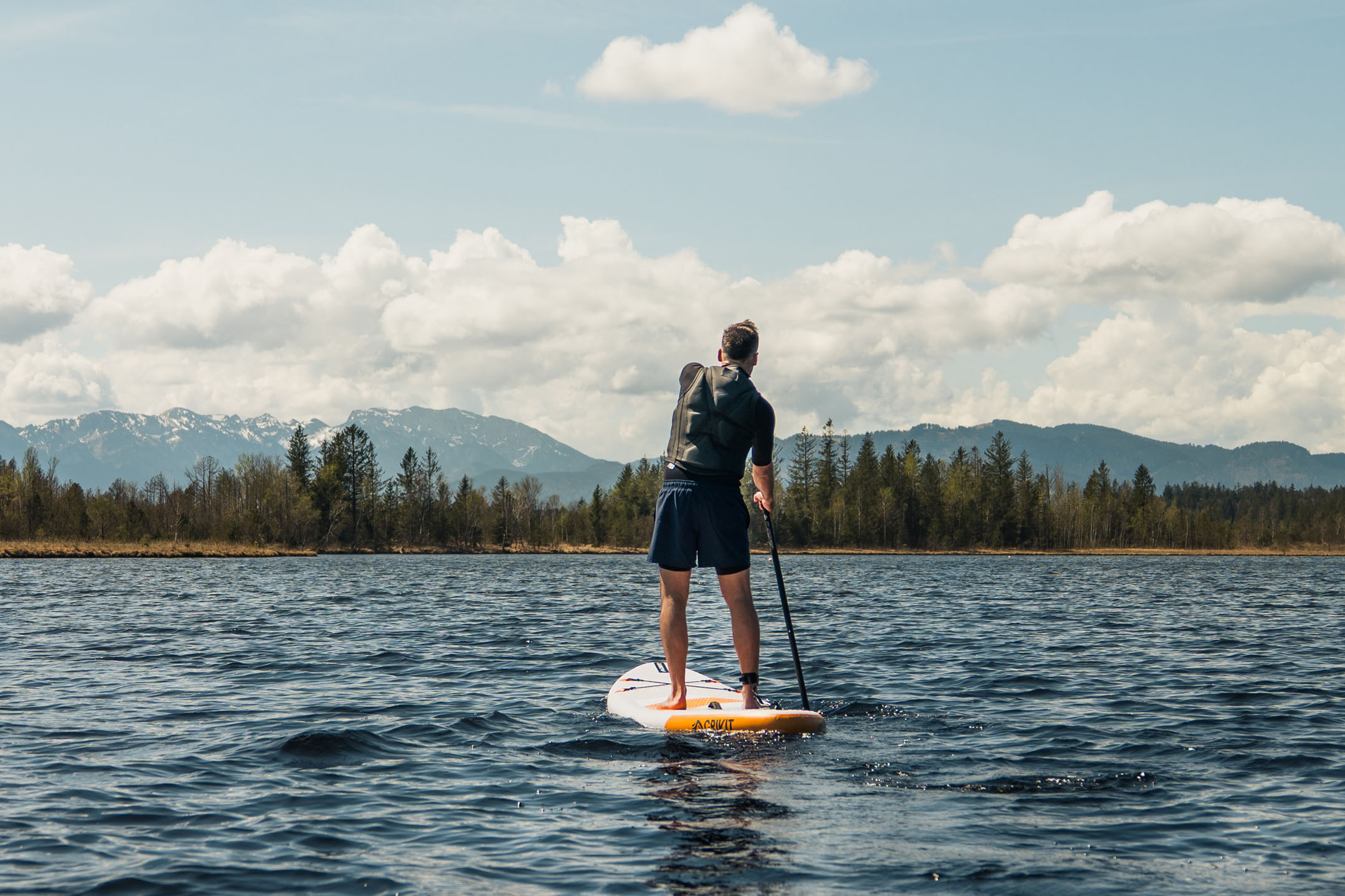 Paddleboarding num lago com montanhas ao fundo.