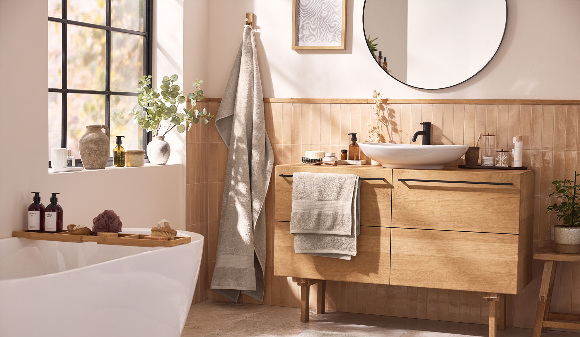 Modern bathroom with wooden bathroom furniture, a bathtub, and a window.